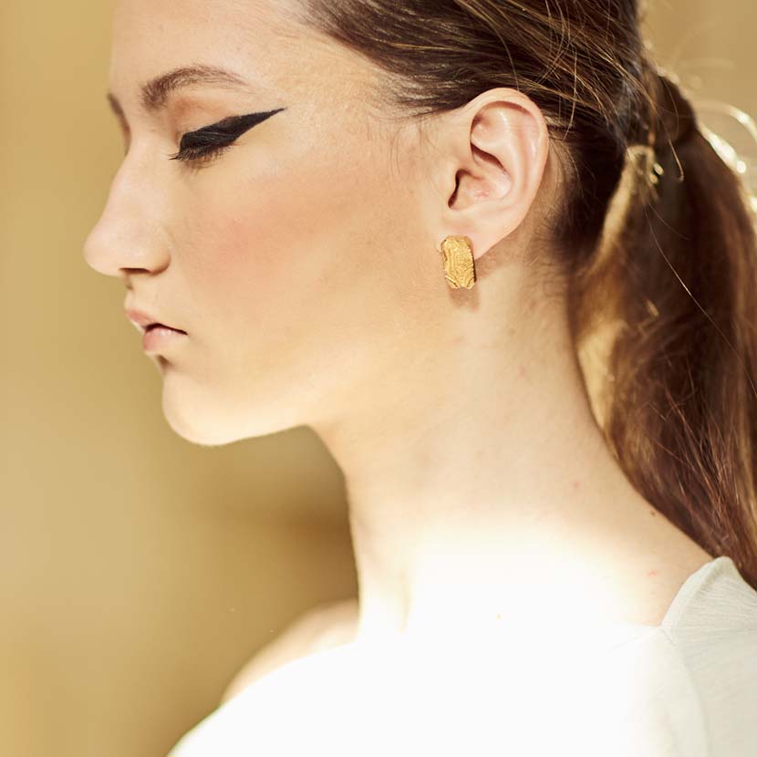 Gold stud earrings on model.