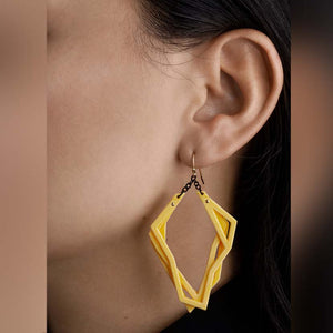 Lightweight statement earrings in yellow on model.