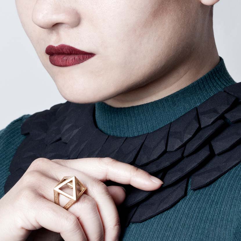 Pyramid ring on finger of woman wearing an Egypt collar necklace.