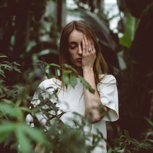 Silver honeycomb ring on hand of woman in between plants.